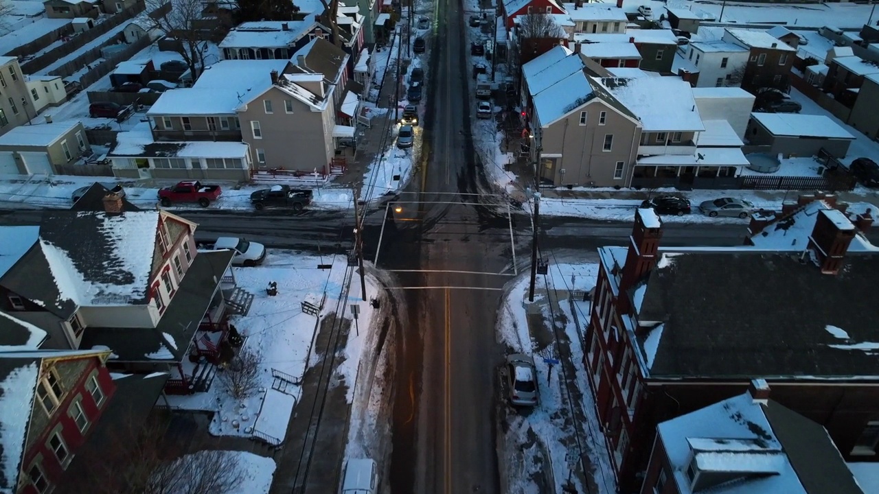 冬季雪后，美国城市直路上空的鸟瞰。白雪覆盖的屋顶和日落时驾驶的汽车。空中前进天桥。视频素材