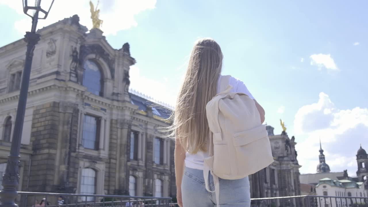 一个女人在城市里背包旅行，凝视着多云天空下的摩天大楼。视频素材