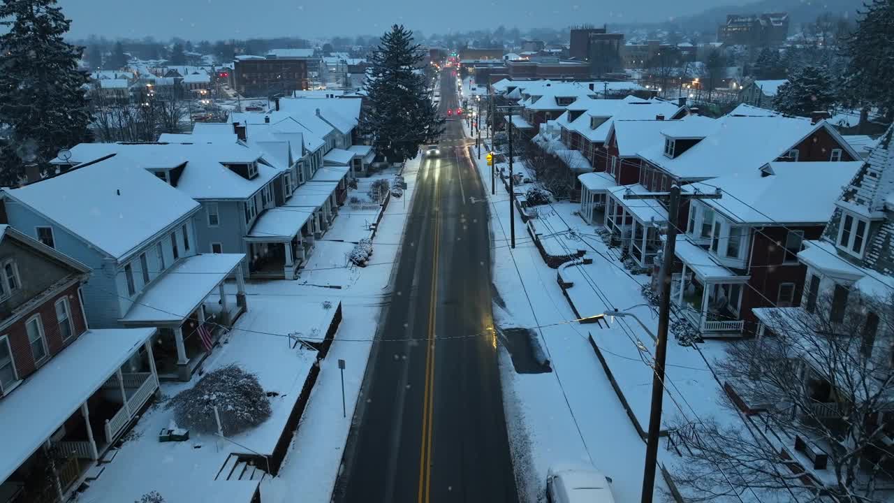 美国的一个小镇，黎明时分的小雪。美国小镇社区的夜晚。美丽的圣诞雪景，被覆盖的城镇房屋排列在灯火通明的街道上。视频素材