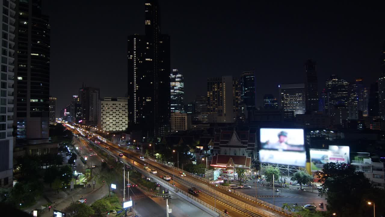 一个繁忙的城市景象的夜间全景，展示了车辆的连续运动和照亮的城市天际线视频素材