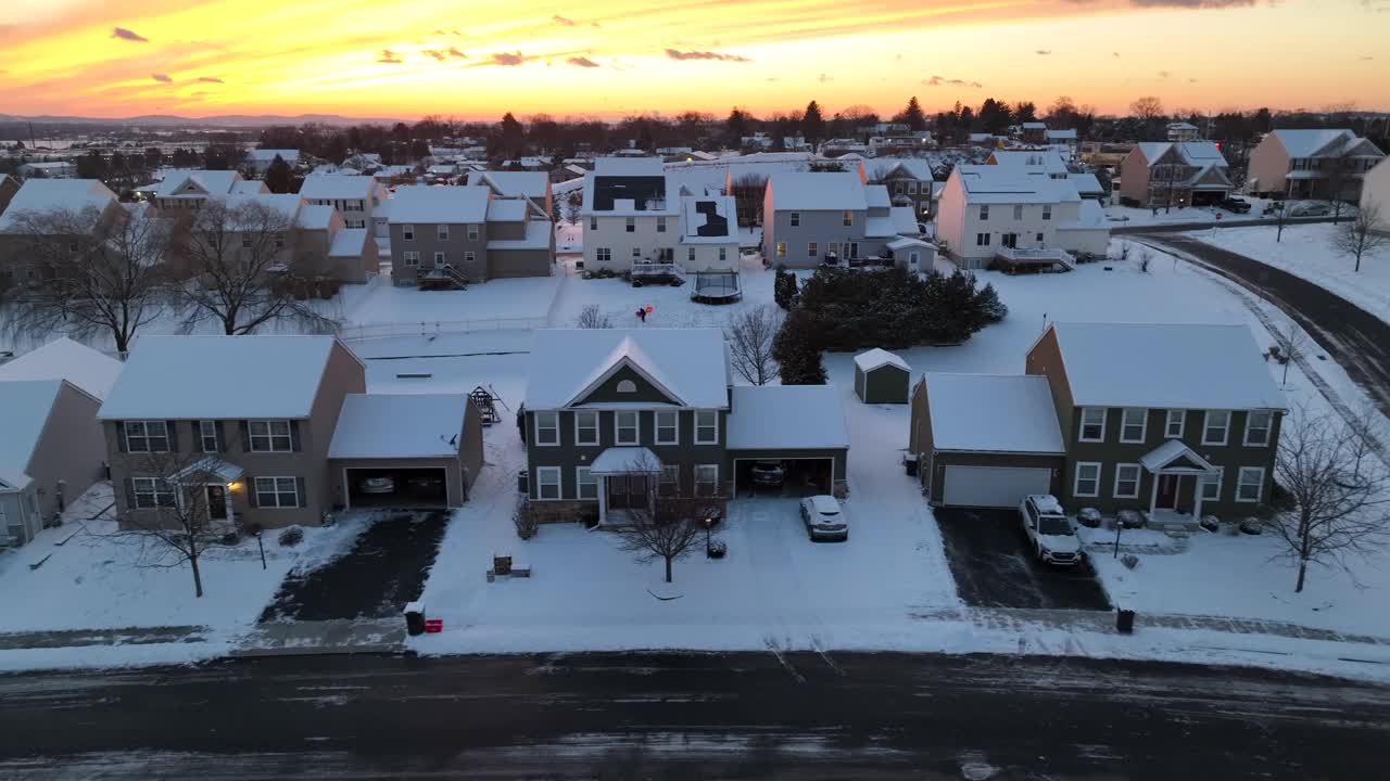 白雪皑皑的夕阳下的现代社区。冬天，美国郊区被雪覆盖的彩色天空。卡车航拍。视频素材