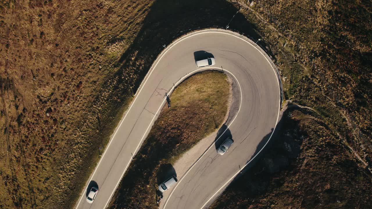 鸟瞰图，一条蜿蜒的道路上骑自行车的人和汽车，周围是崎岖的地形视频素材