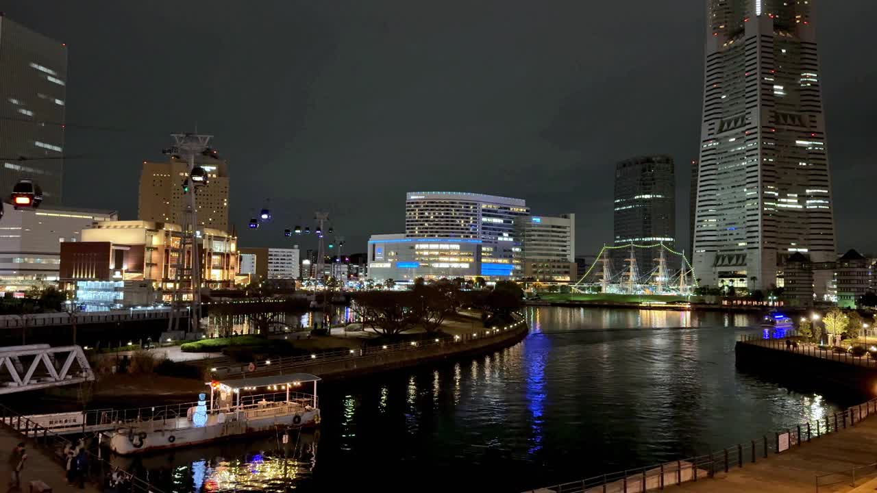 夜晚的城市景观，灯火通明的建筑映在河上，充满活力的城市生活视频素材