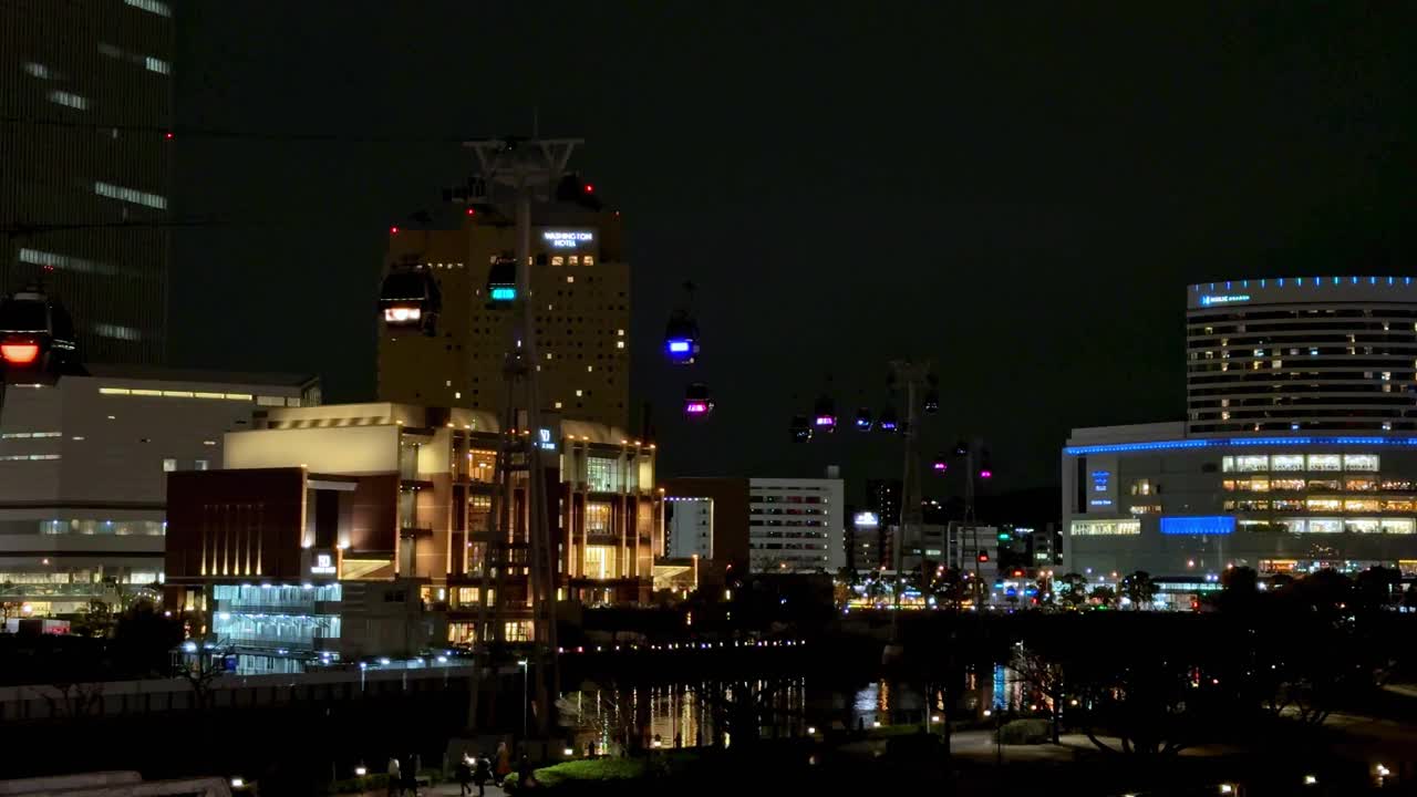 夜晚的城市天际线，明亮的灯光反射在水面上，建筑起重机点缀在背景中视频素材