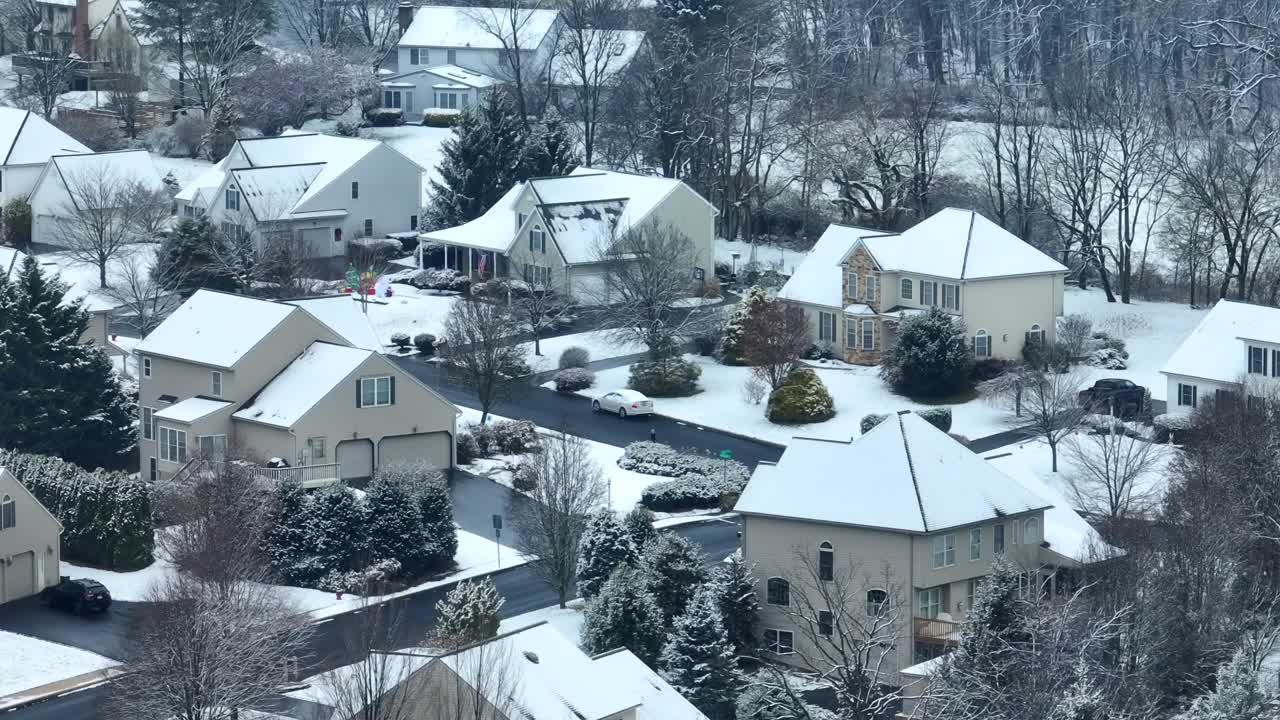 白雪覆盖的郊区住宅，光秃秃的树木和安静的街道。在下雪的冬日，美国附近的空中视差。视频素材