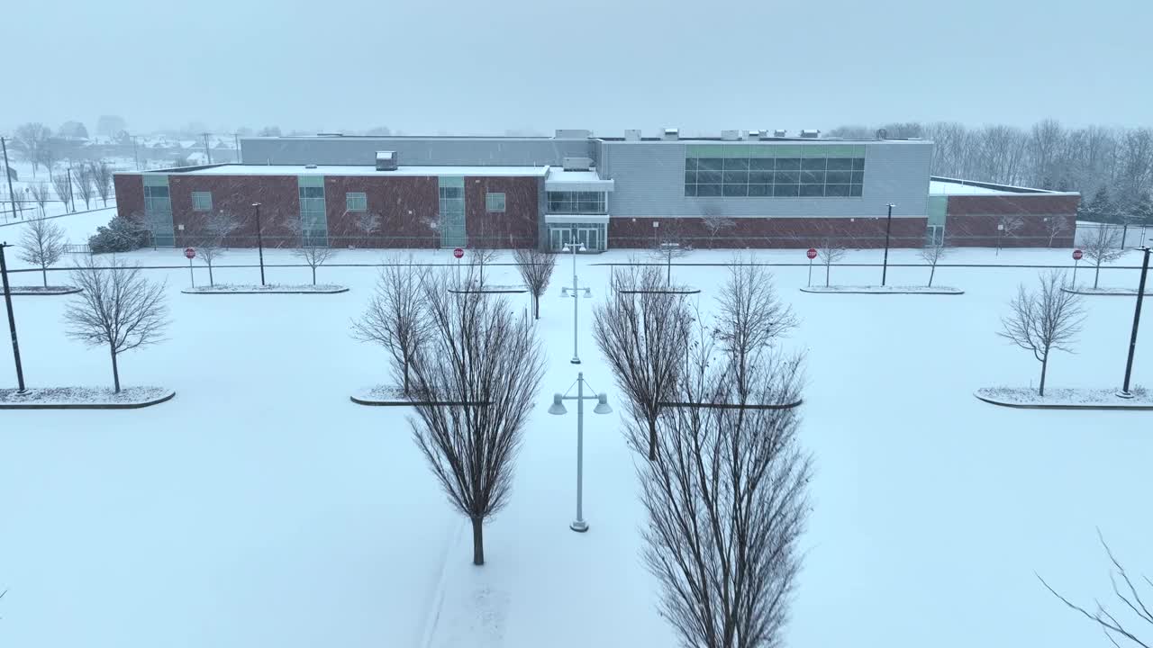 暴风雪时期的现代美国学校。下雪天空荡荡的被雪覆盖的停车场。空中飞进雪花。视频素材