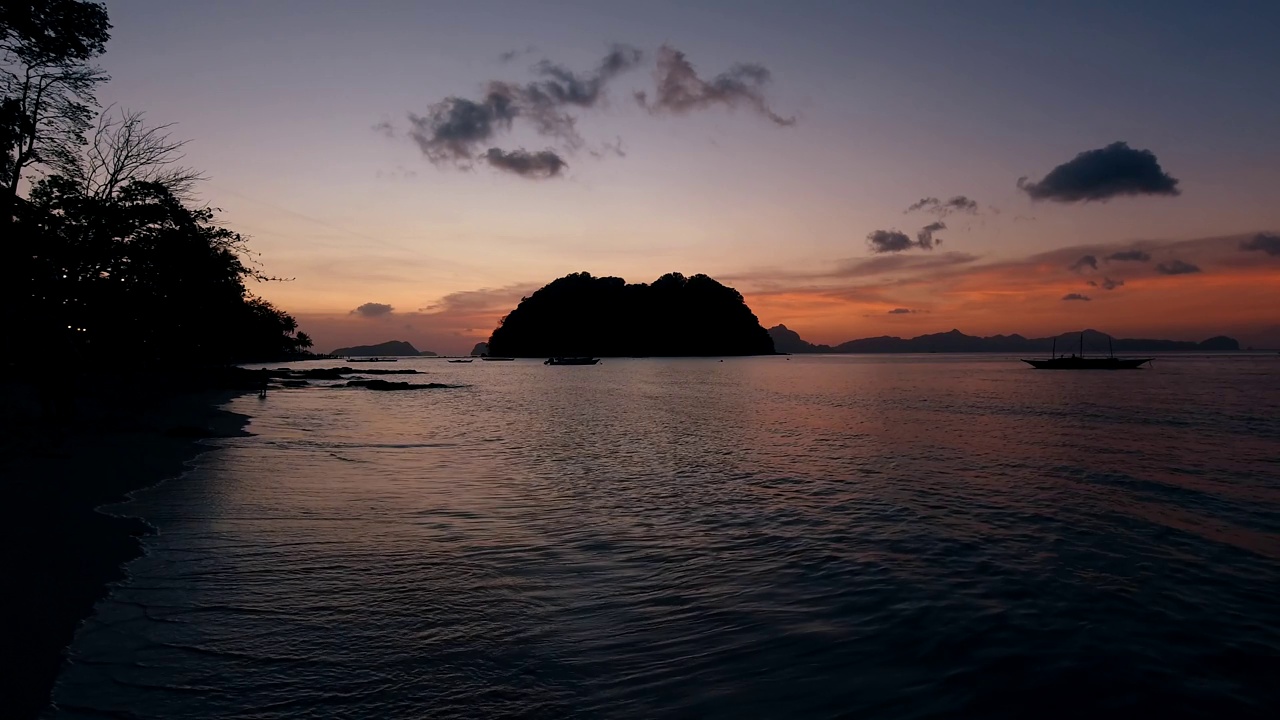 海浪拍打着沙滩。阳光反射在水面上。美丽的傍晚自然大海背景。慢镜头。爱妮岛，菲律宾。视频素材