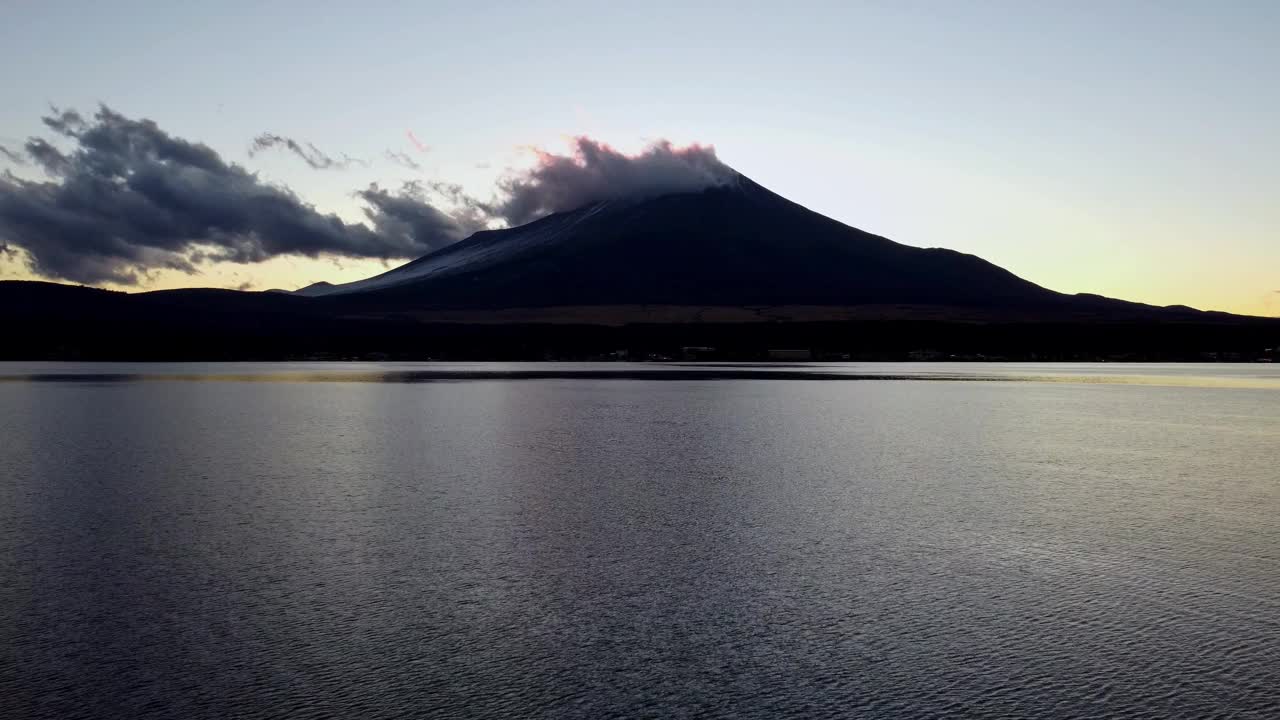 黎明打破了一个宁静的湖与雄伟的山的背景，云轻轻地爱抚它的高峰视频素材