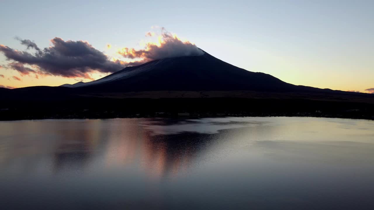 黎明打破了一个宁静的湖与雄伟的山的背景，云爱抚的高峰视频素材