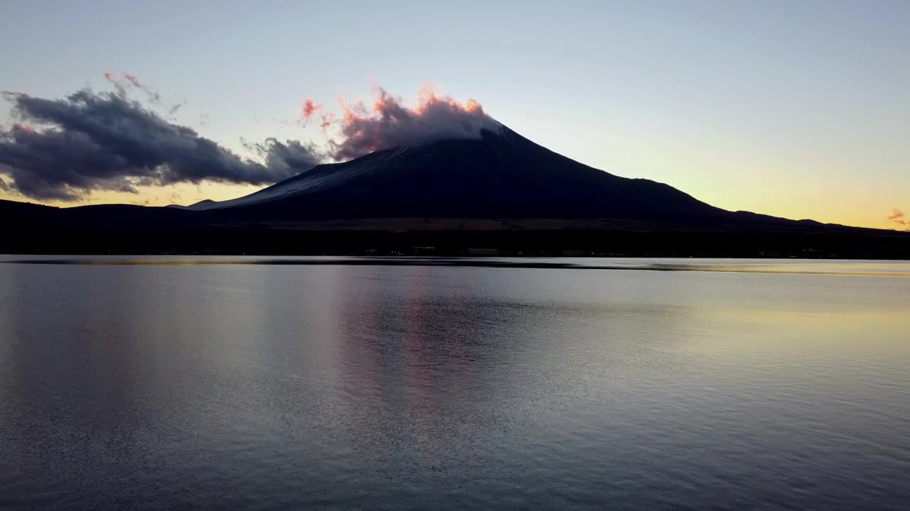 黎明降临在宁静的湖面上，富士山的轮廓映衬着充满活力的天空视频素材