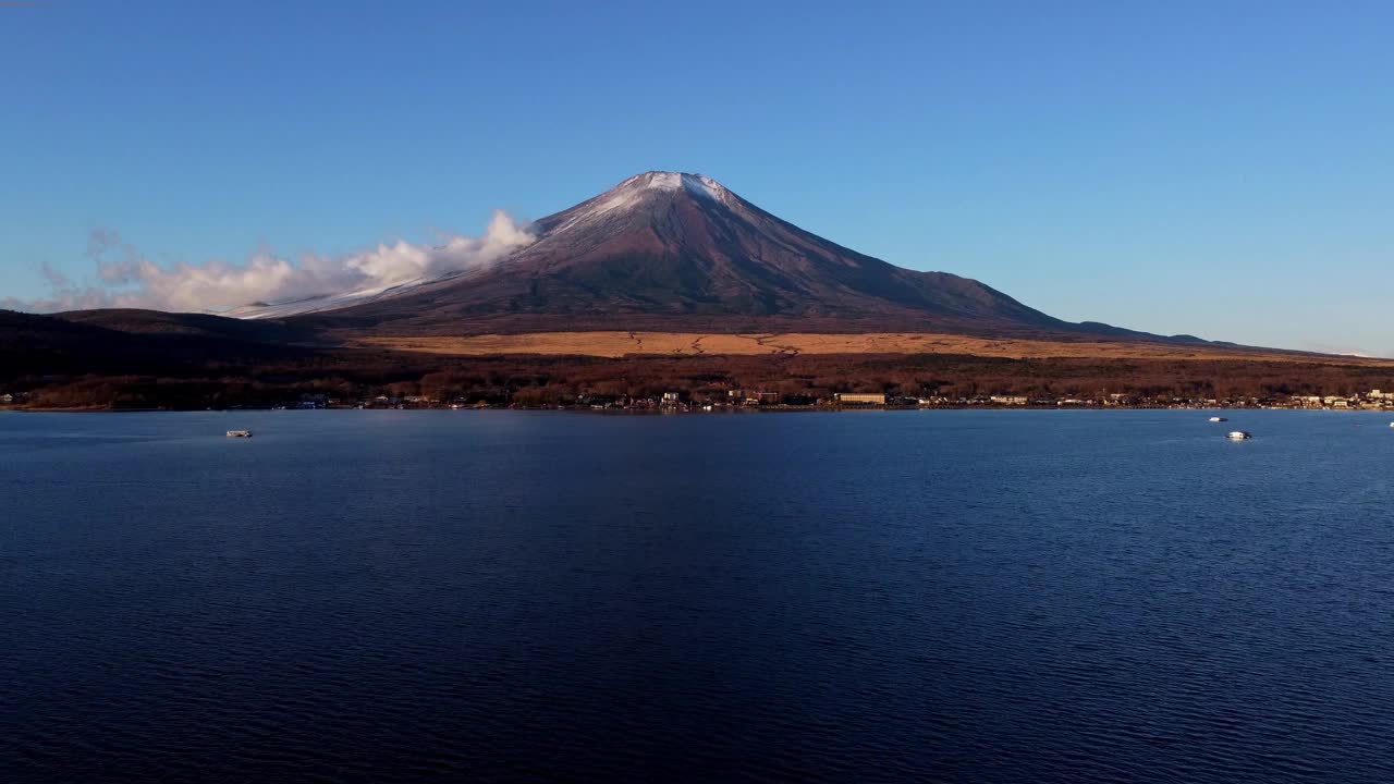 富士山巍峨矗立在碧蓝的天空下，山脚下是平静的湖水视频素材