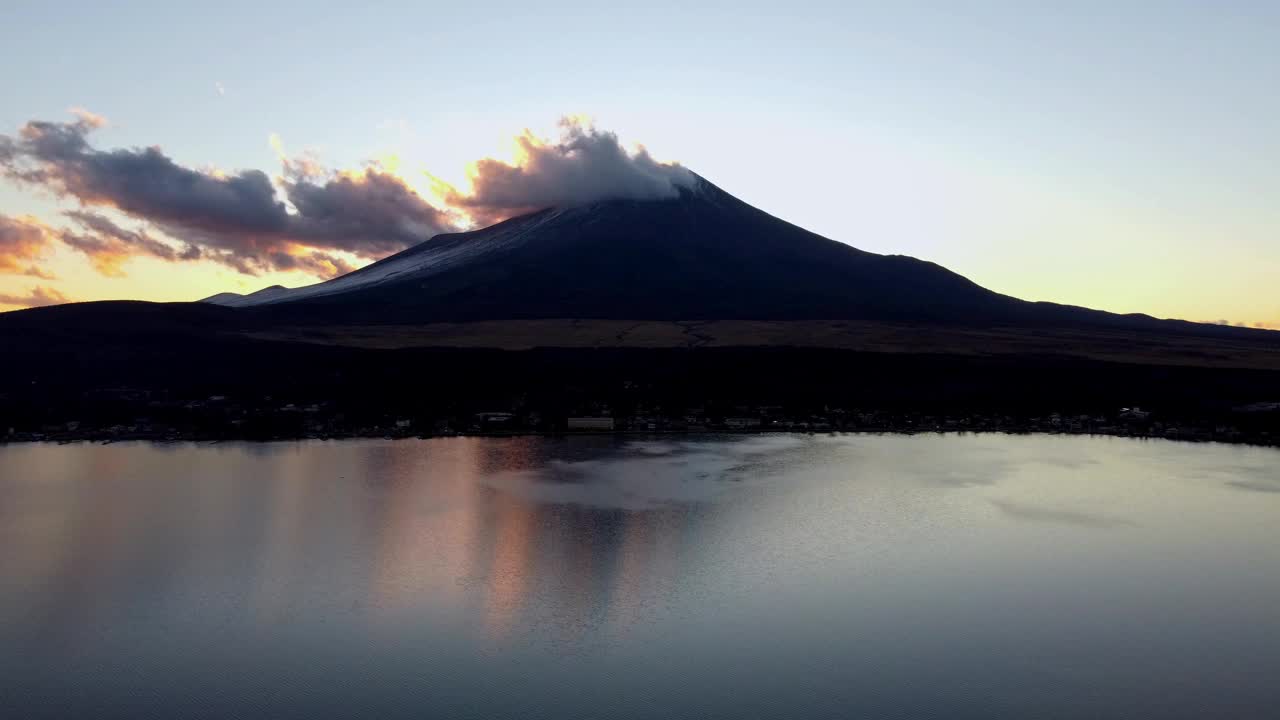 日落时富士山的剪影映在湖面上，云彩飘过视频素材