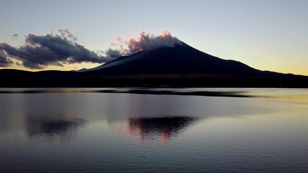 黄昏时富士山的剪影伴着云彩，倒映在平静的湖水中，一派宁静祥和的景象视频素材