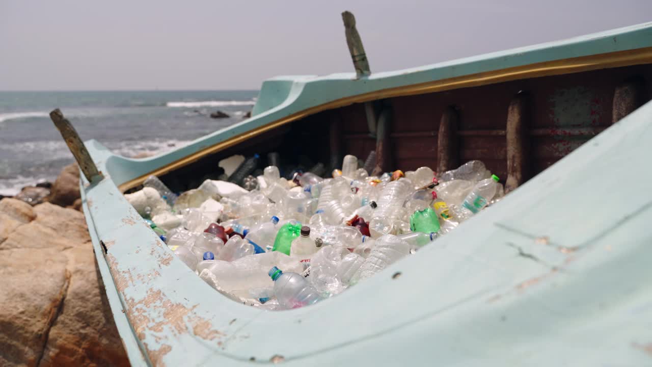 海滩船带塑料瓶，海洋污染危机。垃圾、垃圾、垃圾场的人类塑料垃圾管理回收生态问题。海岸背景，海浪冲击海岸。视频素材