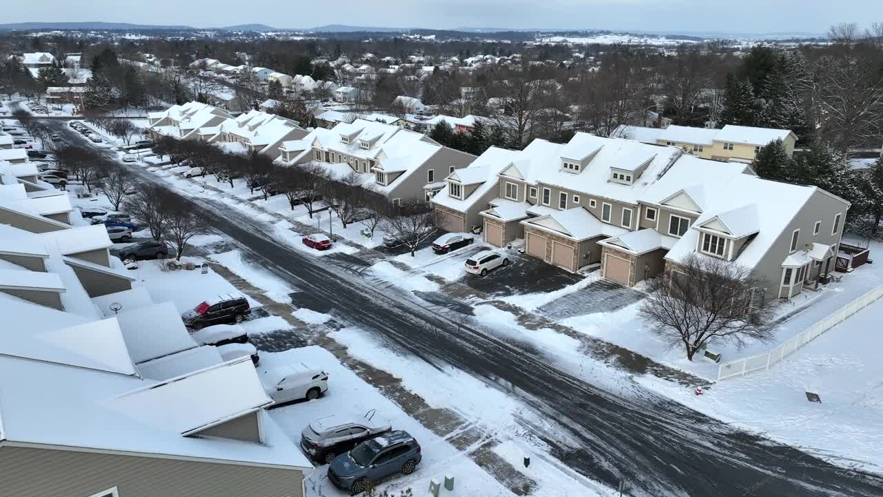 白雪皑皑的社区，整齐划一的房子和停在空旷街道两旁的汽车。冬季的美国附属房屋。航拍积雪覆盖的景观。视频素材