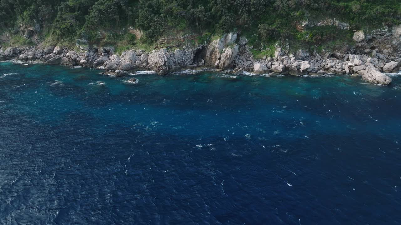 意大利卡普里岛的海岸线，郁郁葱葱的绿色植物和岩石悬崖，蔚蓝的大海，日光视频素材