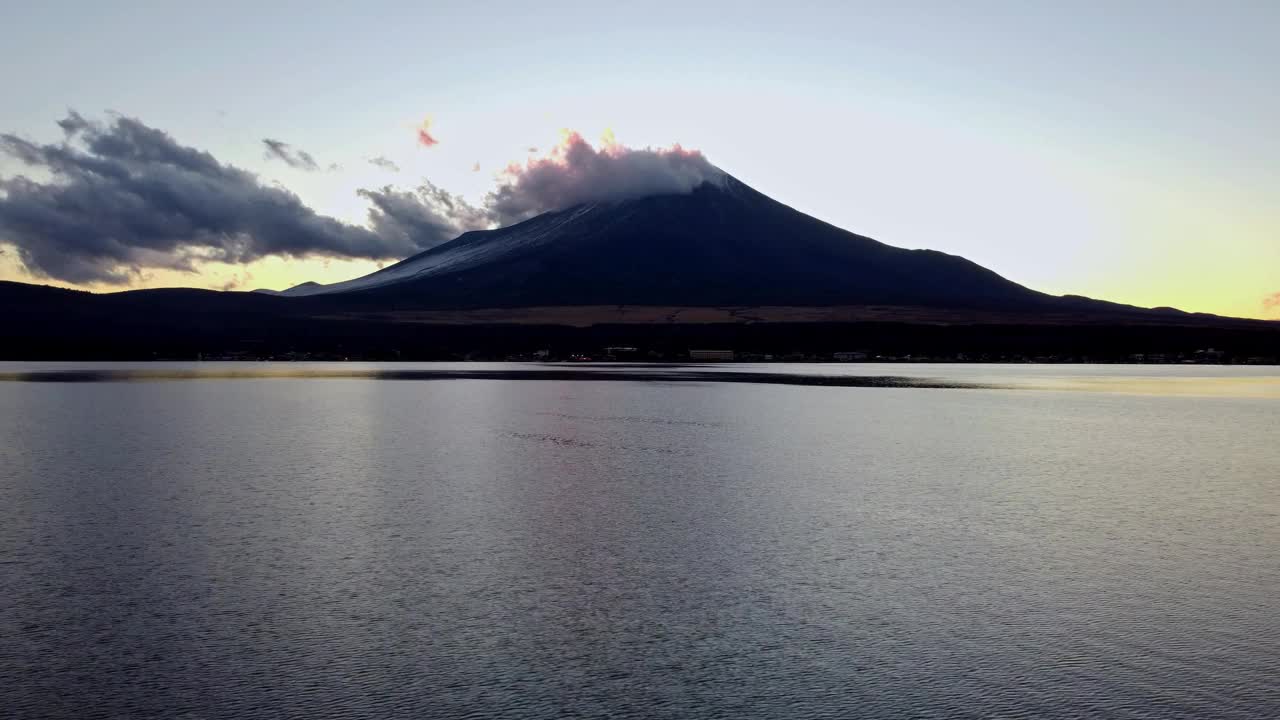 黎明降临在宁静的水面上，背景是富士山，云轻轻地掠过视频素材