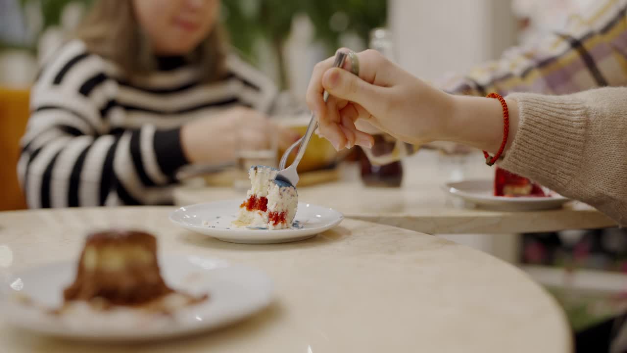 女人们坐在咖啡桌旁，品尝着美味的奶油饼干蛋糕视频素材