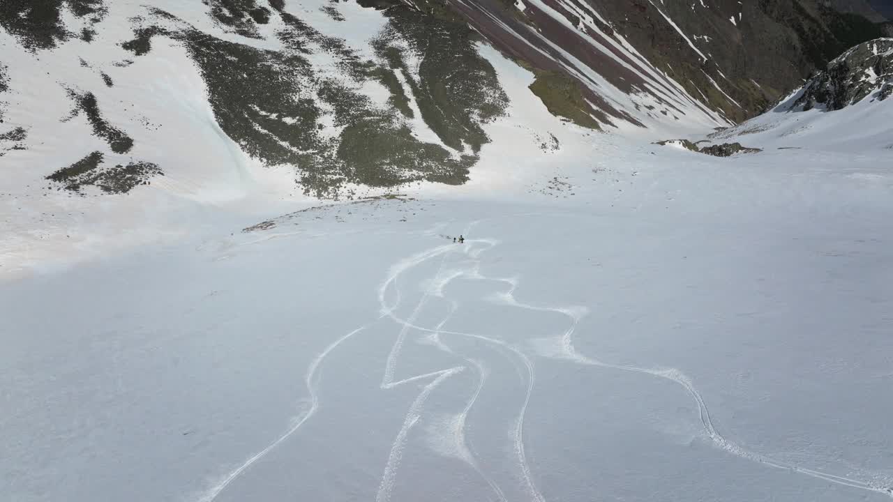 鸟瞰滑雪自由式滑雪者在雪山的高处在朋友的陪伴下下坡视频素材