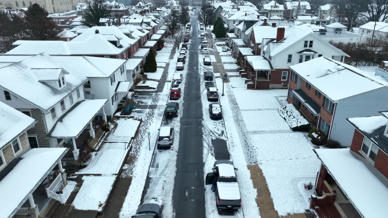 在美国社区狭窄的街道上停车。冬天房屋和建筑物的积雪屋顶。空中鸟眼向后拍摄。视频素材