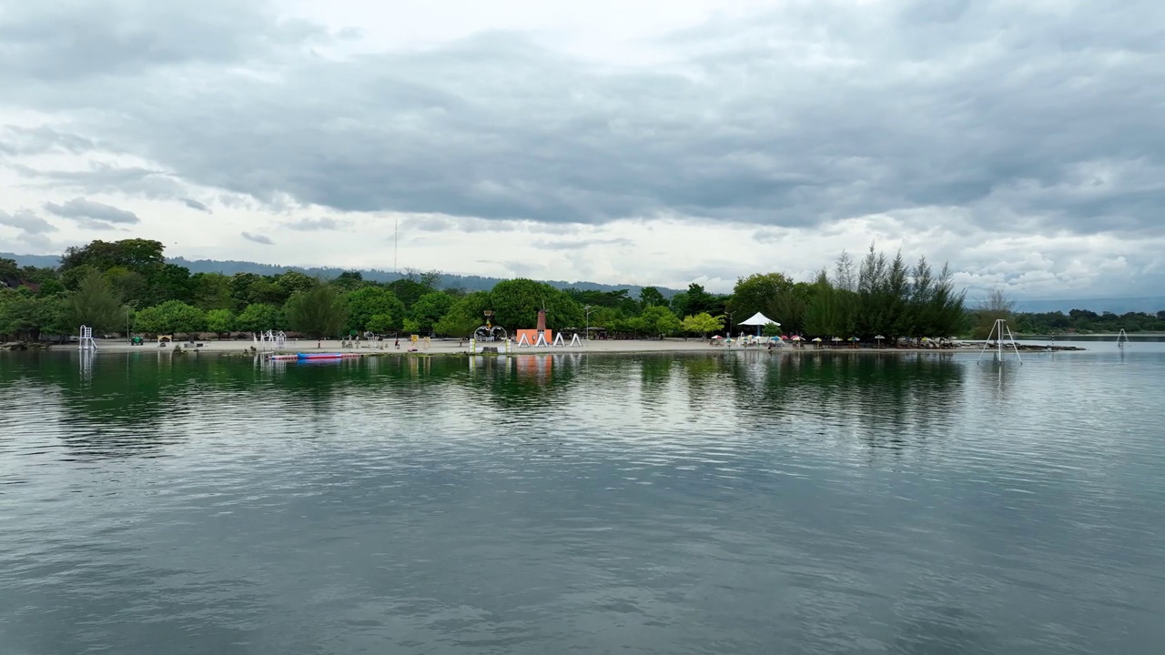 印尼苏门答腊岛，多巴湖Pantai Batuhoda平静的水域，多云的天空和郁郁葱葱的绿色植物视频素材