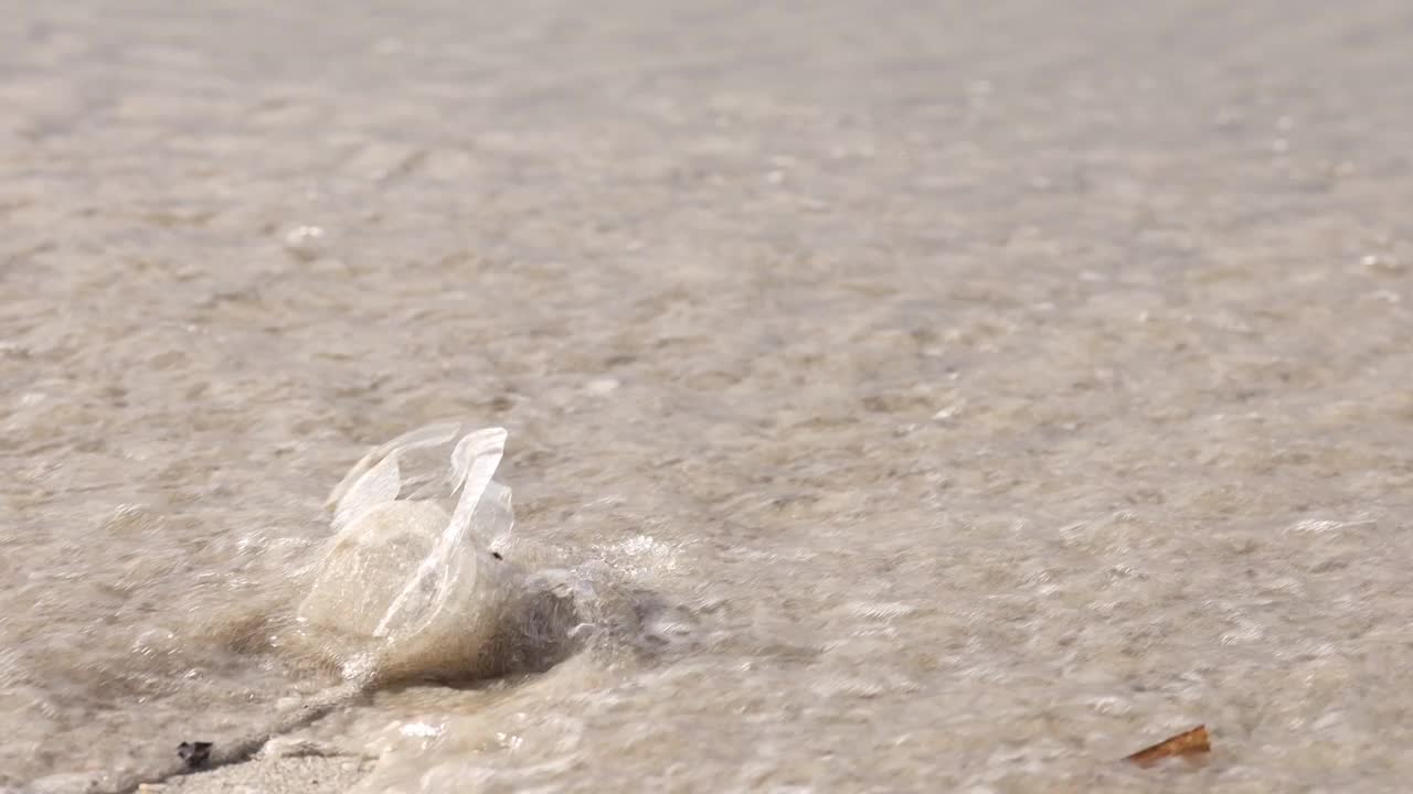 破碎的塑料杯被海水冲走，主题是环境污染视频素材