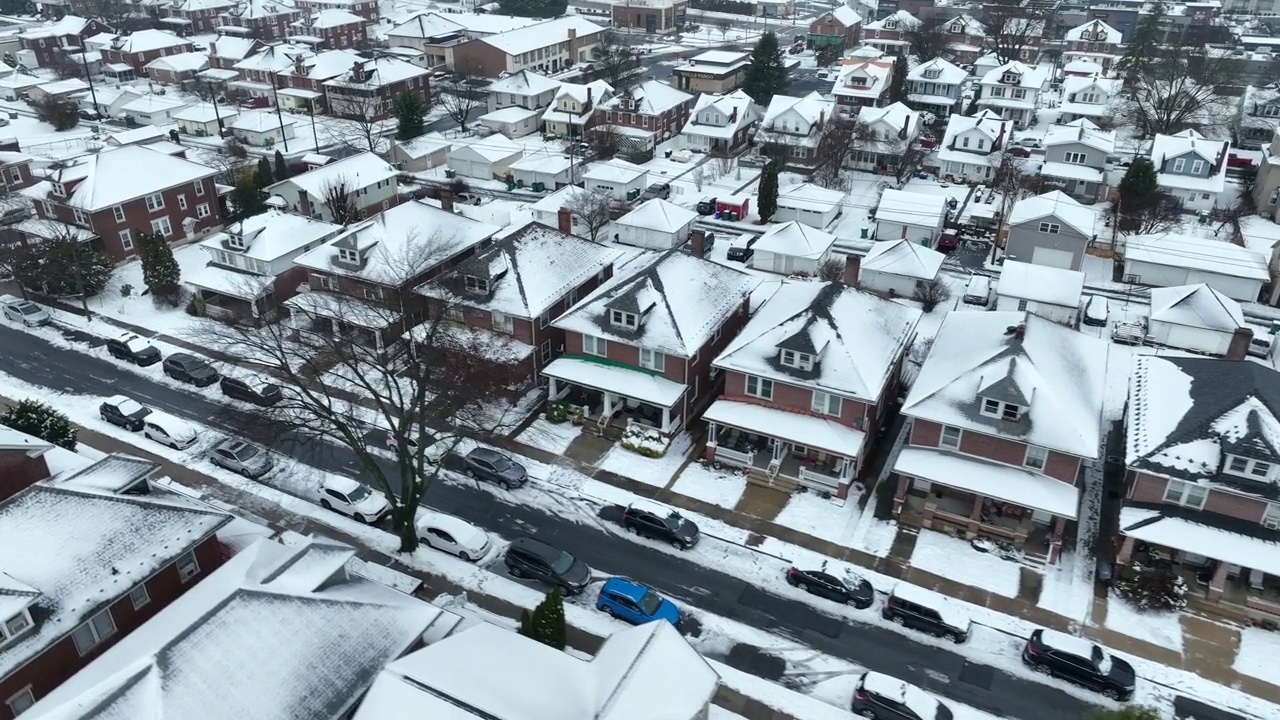 在暴风雪过后的夜晚，电影般的无人机在被雪覆盖的美国村庄上空飞行。积雪覆盖的停车场。圣诞节时美国美丽的小镇。空中俯视立交桥。视频素材