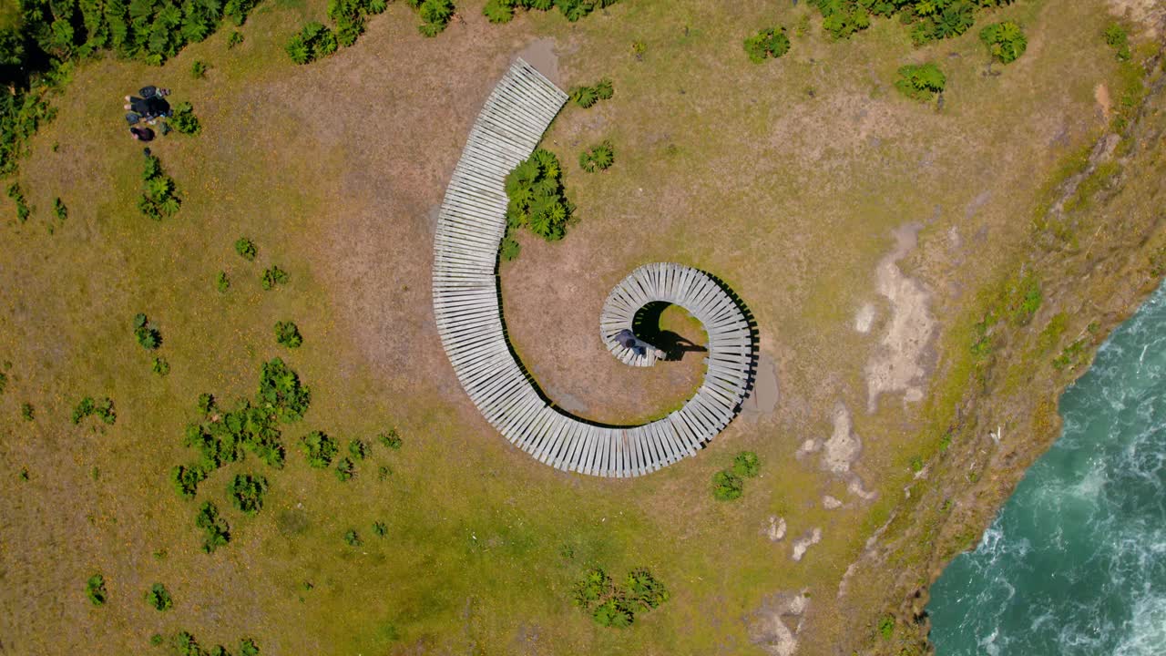 空中无人机在螺旋木路径上旋转，Muelle del Tiempo，绿色海岸波浪，chilo<e:1>海滩景观，智利巴塔哥尼亚，灵魂码头视频素材