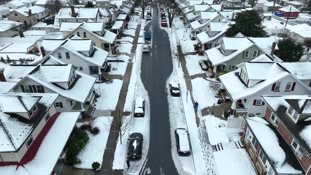 在美国住宅区，人们正在清理人行道上的积雪。在美国，冬天的雪和停车的汽车。空中鸟瞰图。视频素材