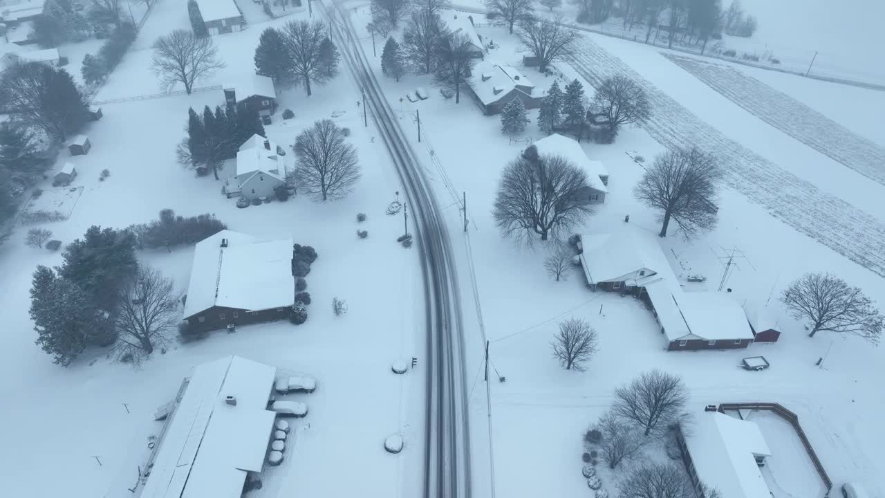 空中鸟瞰在美国被雪覆盖的村庄。多云阴天的暴风雪和降雪。视频素材