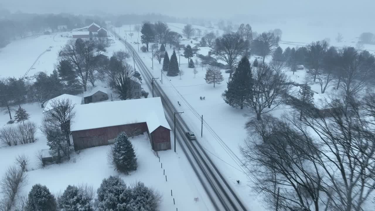 在美国乡村的雪地上驾驶汽车。暴风雪覆盖着田野。无人机跟随广角镜头。视频素材