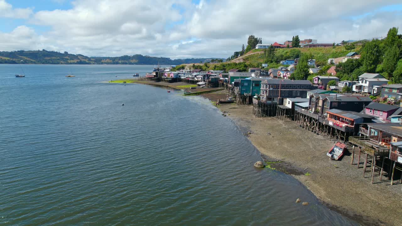 多利在智利卡斯特罗的彩色高跷房屋的海岸上空。阳光明媚的一天，智利南部的旅游景点。视频素材