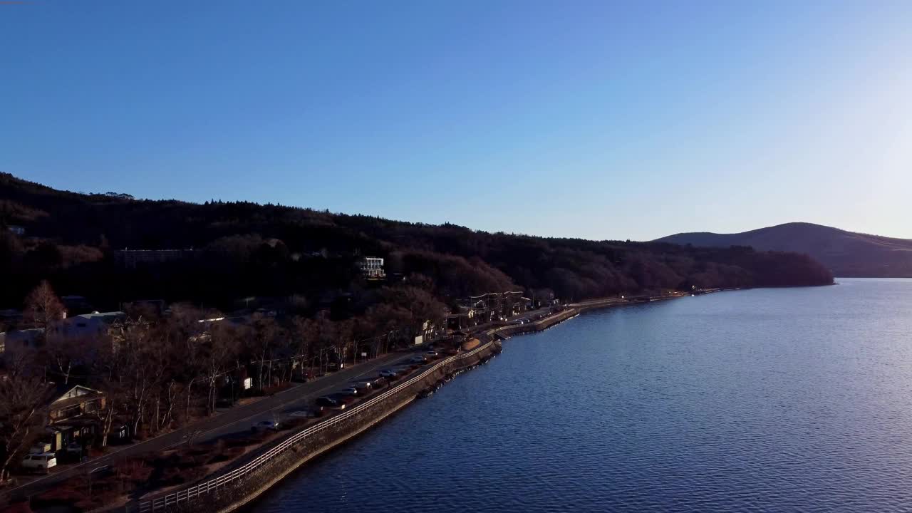 沿海公路沿着平静的海湾蜿蜒而行，有山丘，黄昏时天空晴朗，鸟瞰视频素材