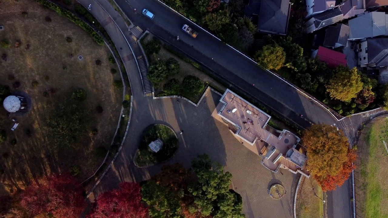 弯弯曲曲的道路和建筑物，黄昏时的秋天树木，鸟瞰图视频素材