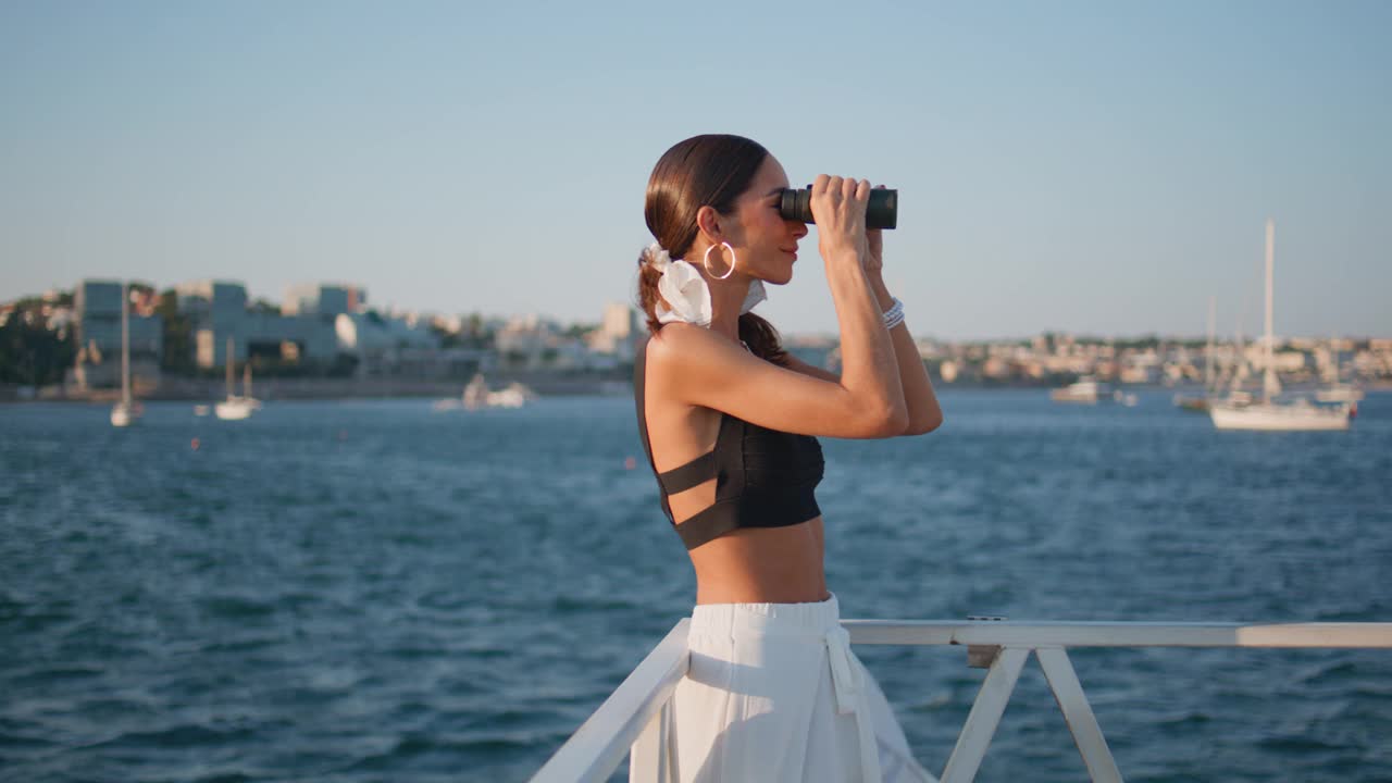 用双筒望远镜看夏天海边美景的女人。站在海滨的女孩视频素材