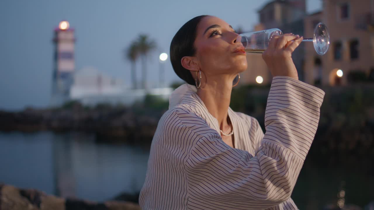 浪漫的女人在晚上喝鸡尾酒的海岸近距离。品酒的女孩视频素材