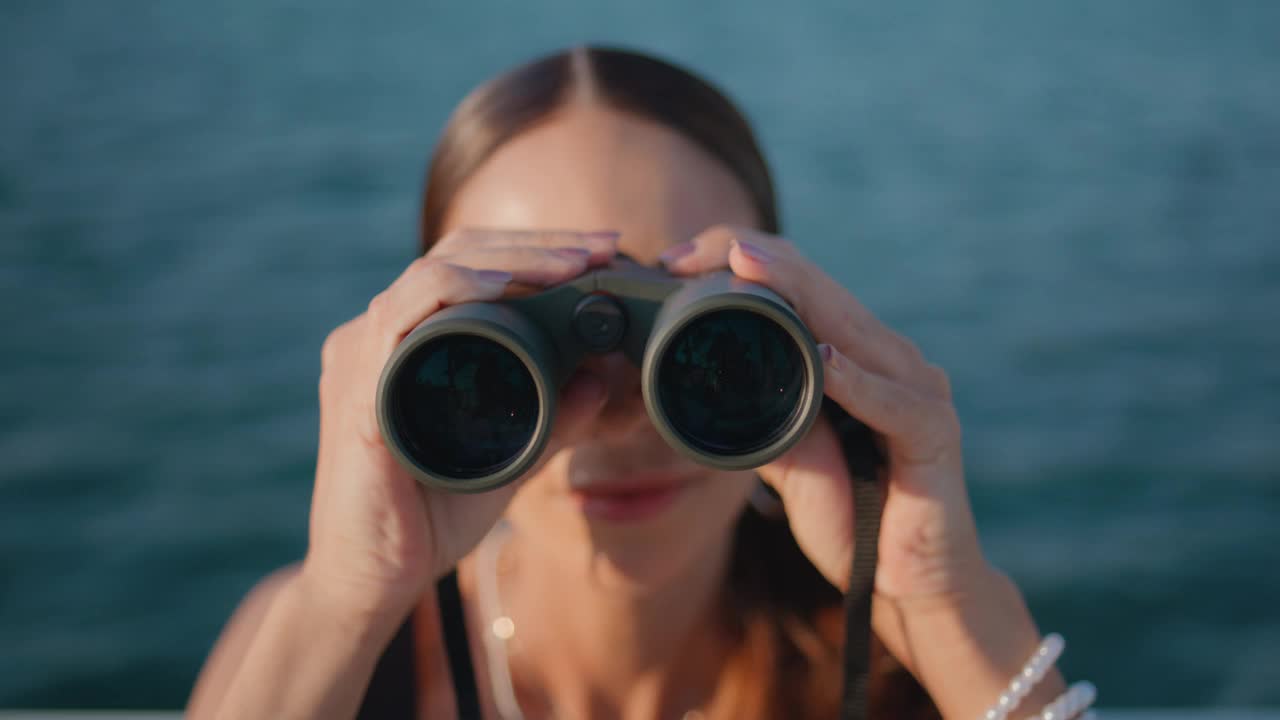 女人用双筒望远镜看暑假的海景特写。女孩的旅行视频素材