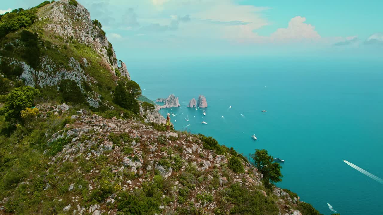 悬崖边小径俯瞰宁静的海洋景观。在多云的天空下，蓝绿色的海面上点缀着船只。视频素材