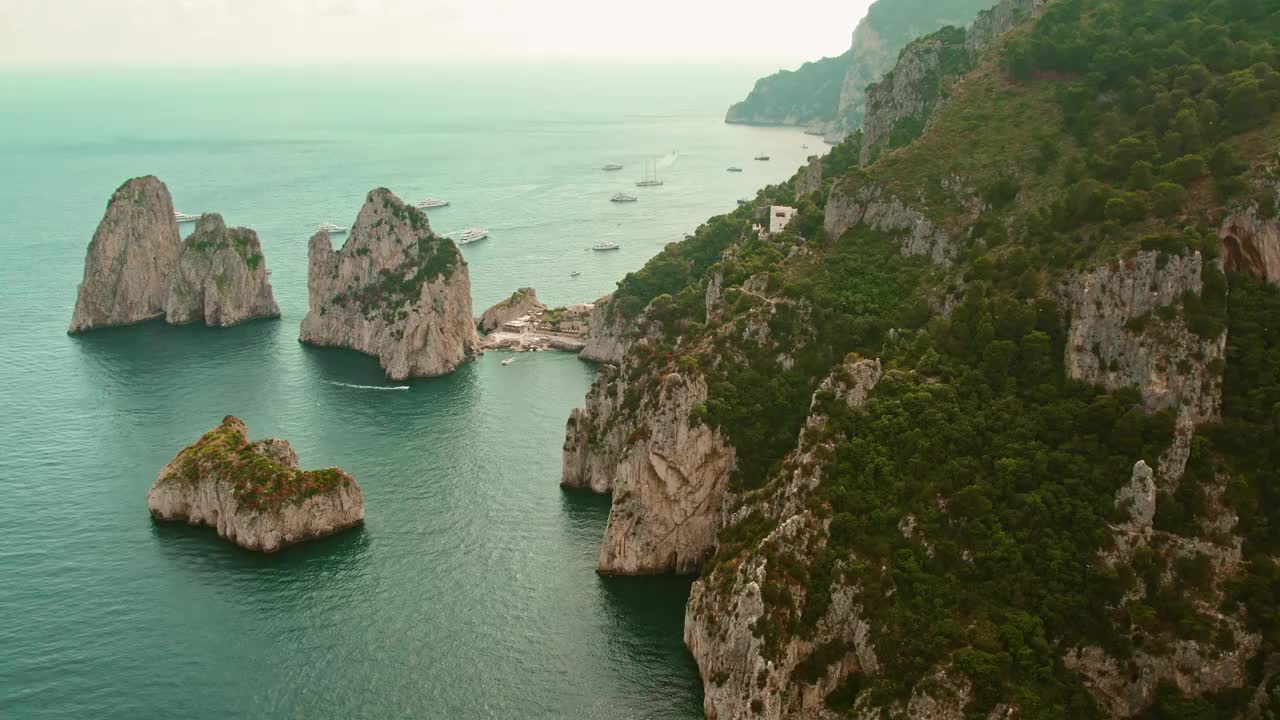 宁静的海湾坐落在戏剧性的岩层和郁郁葱葱的山坡之间。幽静的海湾点缀着休闲船只，下面是隐蔽的海滩。视频素材