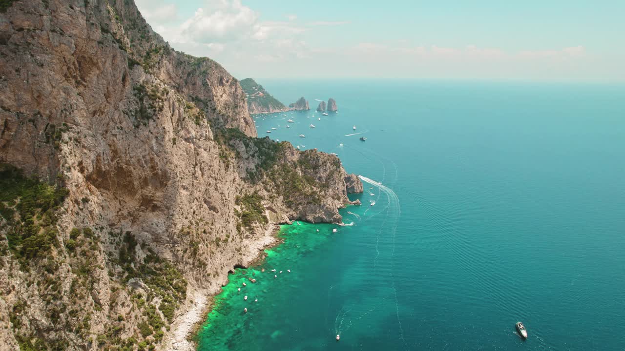 卡普里岛崎岖的海岸线俯瞰着生动的大海，法拉格里奥尼海柱附近点缀着船只。鸟瞰湛蓝的海水。视频素材