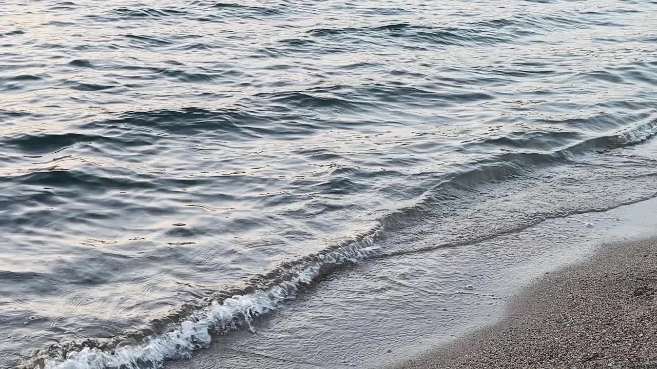 黄昏时，柔和的海浪冲刷着鹅卵石沙滩，夏日出游视频素材