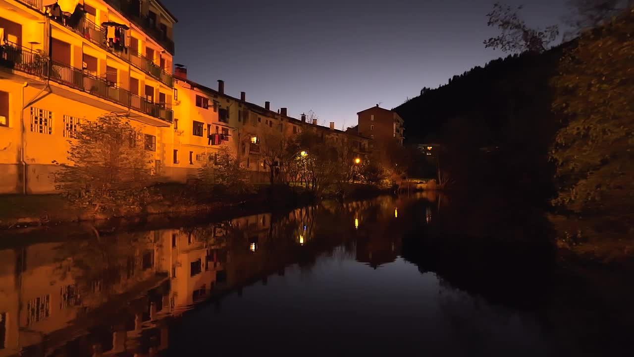 夜间在西班牙巴尔马塞达的中世纪石桥下向后飞行的无人机视频素材