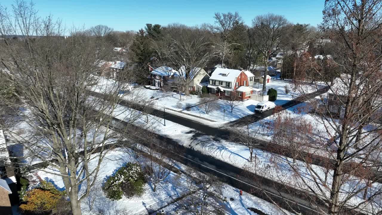 美国住房区冬季积雪郊区。阳光明媚的一天，屋顶被雪覆盖。空中接近射击。视频素材