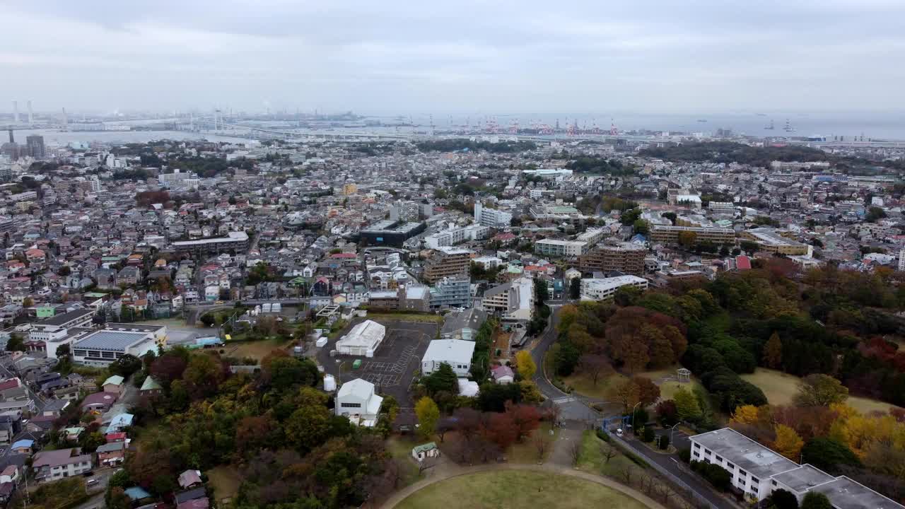 在多云的天空下，密集的城市景观与散落的绿色植物，暗示城市蔓延，鸟瞰图视频素材