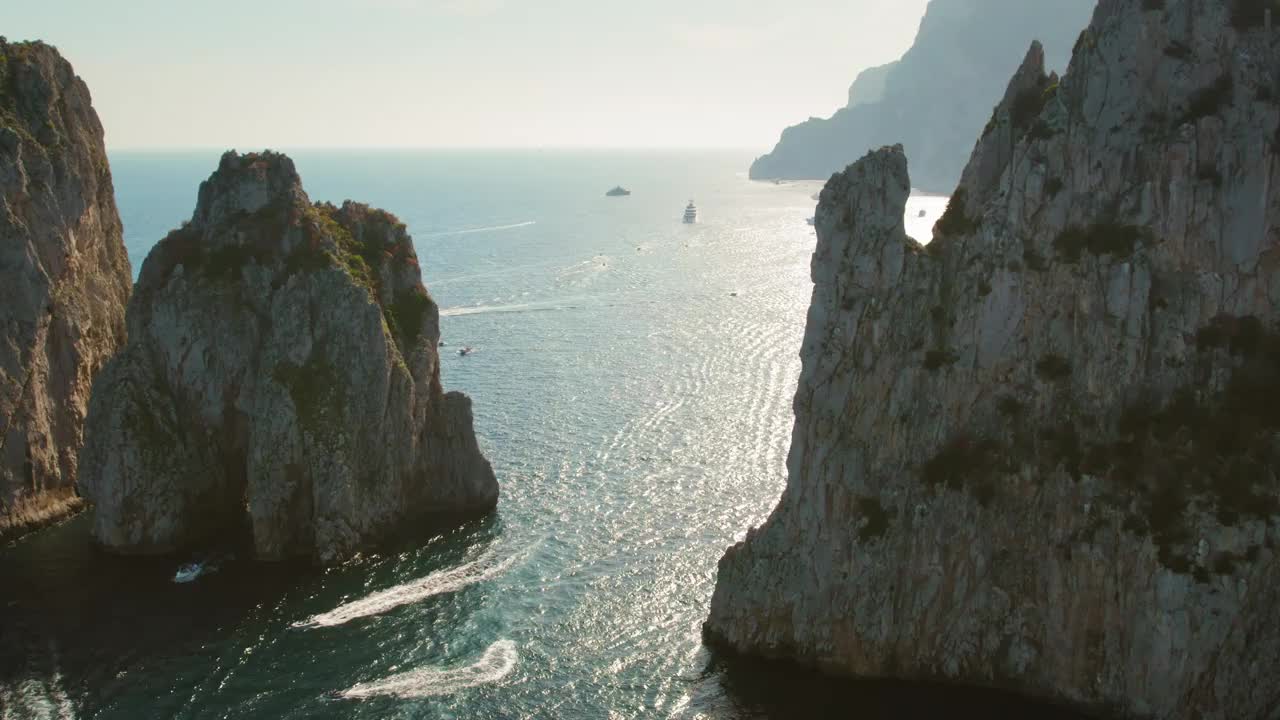 卡普里岛崎岖的海岸线沐浴在阳光下，海上交通显示了繁忙的一天。法拉格里奥尼悬崖耸立在海景之上。视频素材