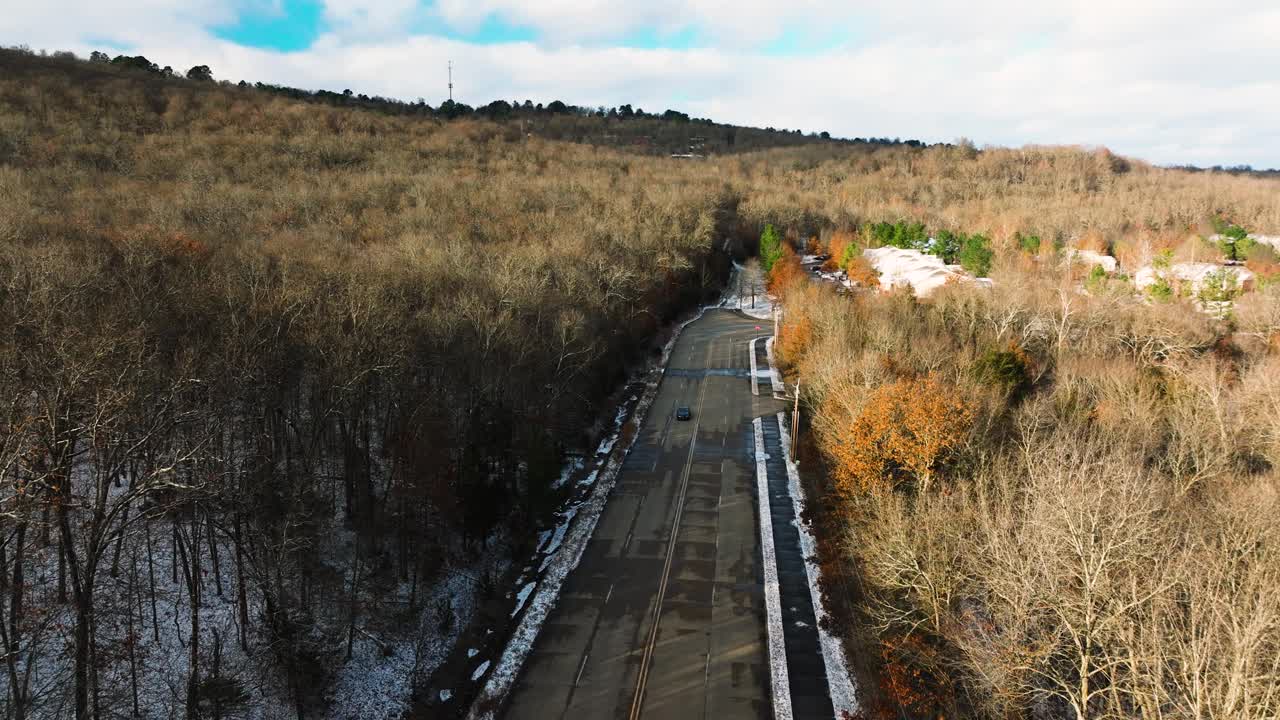 汽车行驶在空旷的道路上，冬日的光秃秃的森林，阳光明媚，航拍视频素材