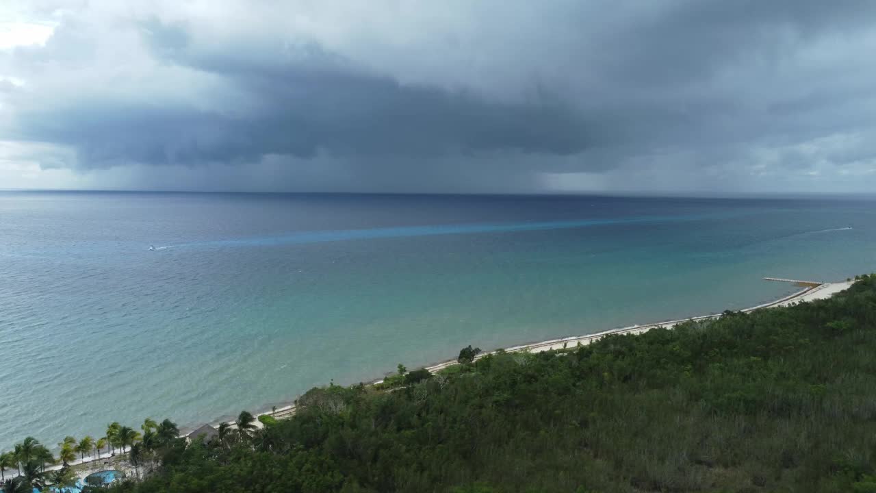 墨西哥，加勒比海科苏梅尔岛郁郁葱葱的海岸，背景是暴风雨的天空。空中侧边和复制空间视频素材