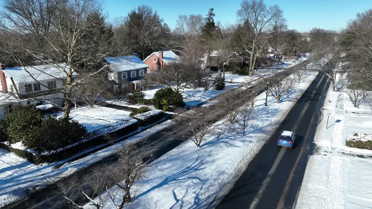 在冬天的雪天，在美国小镇的路上开车。树木和前花园都被雪覆盖着。宾夕法尼亚州兰开斯特郊区。鸟瞰图。视频素材