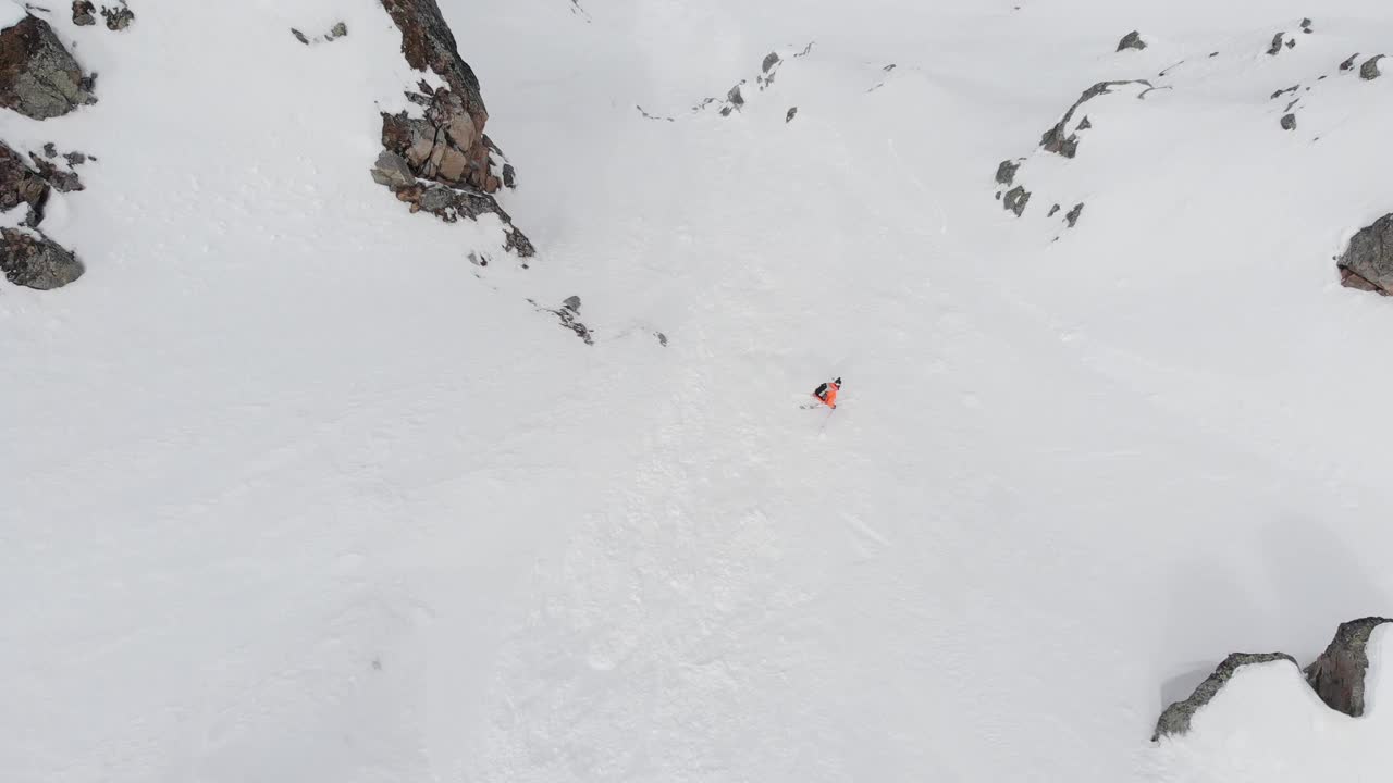 空中无人机滑雪者和单板滑雪者在雪山的极端斜坡上滑雪，跳跃，自由骑行视频素材