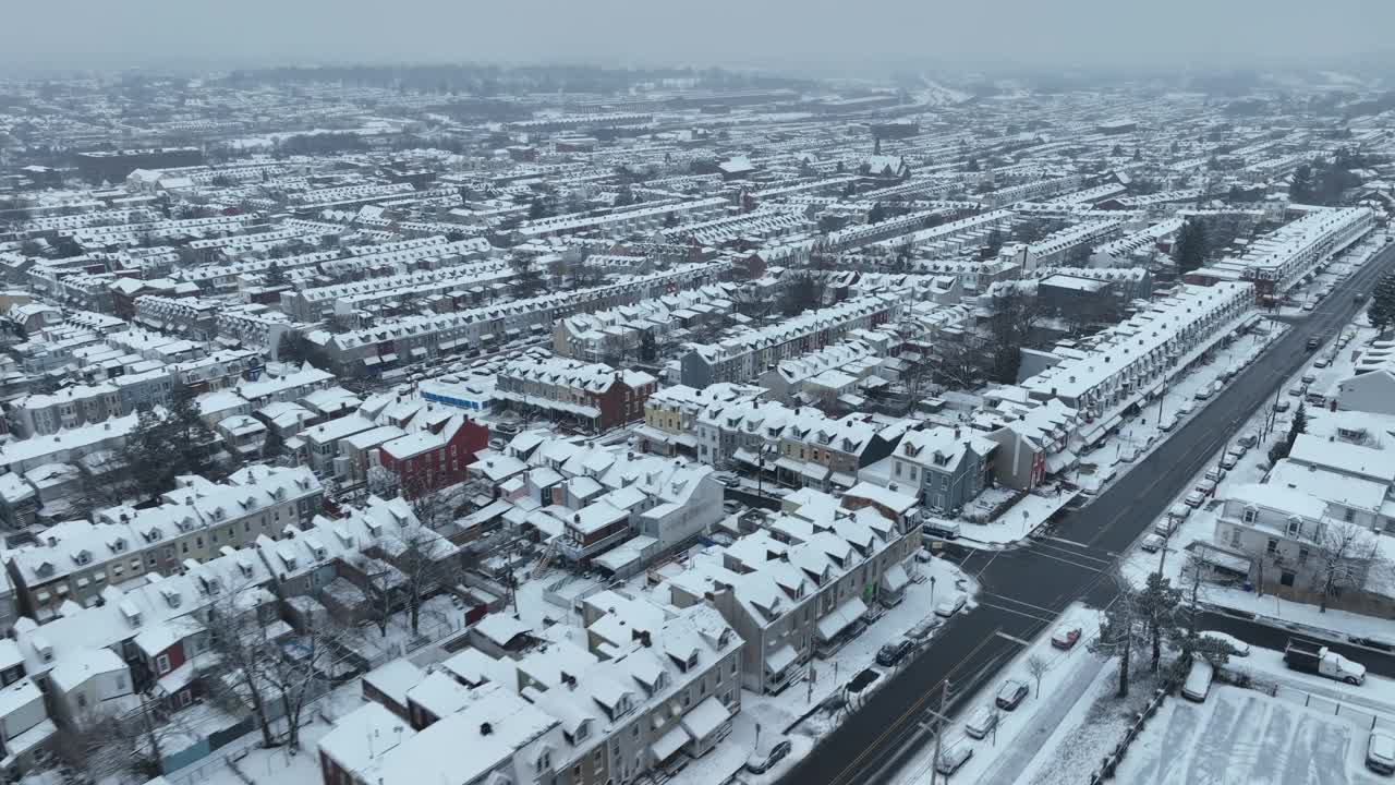 电影般的无人驾驶飞机在美国住宅区上空飞行，在冬天的雪中有房屋和建筑物。灰色雾蒙蒙的圣诞节。镇上一排排拥挤的房子。视频素材